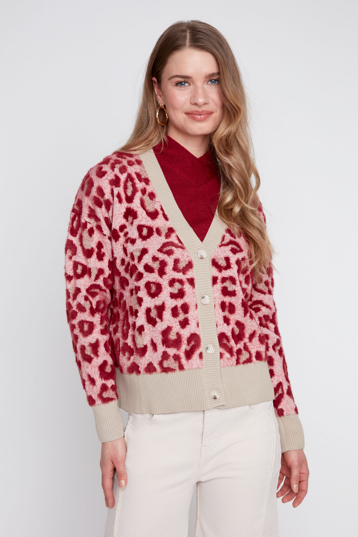Woman wearing the Eloise pink and red leopard print jacquard knit cardigan over a red turtleneck.