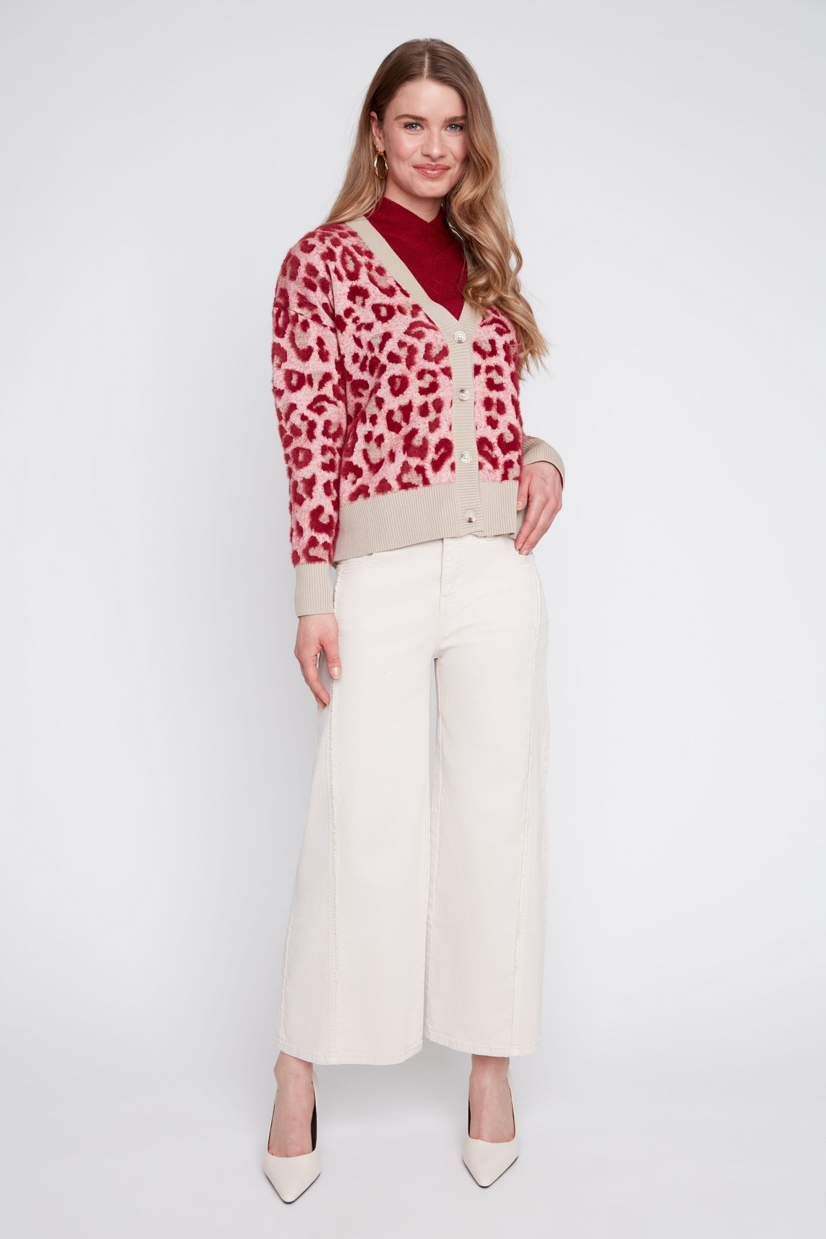 Woman wearing the Eloise red and pink animal print jacquard knit cardigan with cream wide-leg pants.