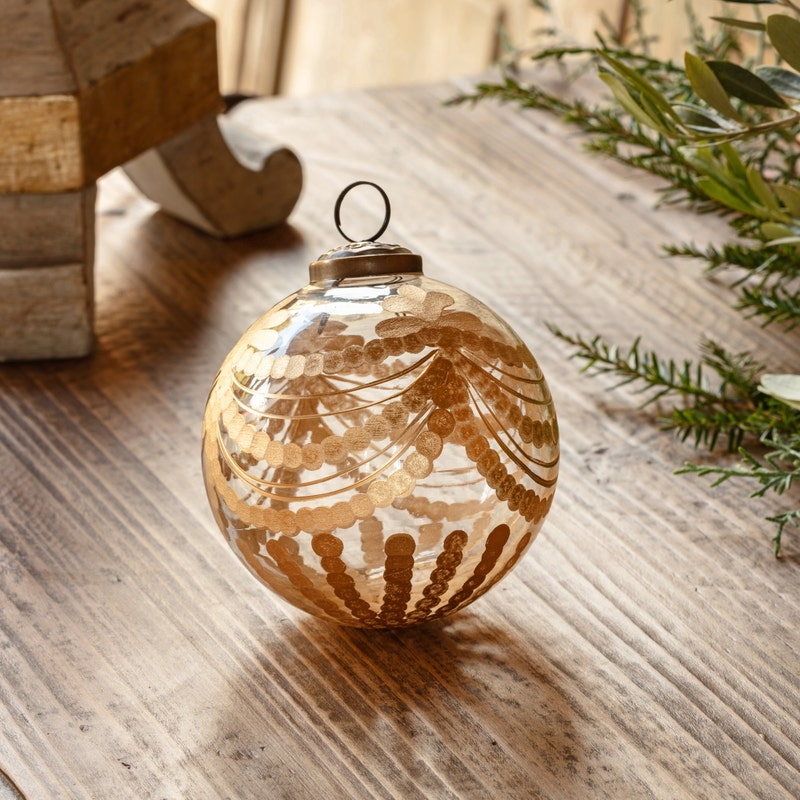 Etched Golden Garland Glass 4" Ornament with gilded details on a rustic wooden surface.