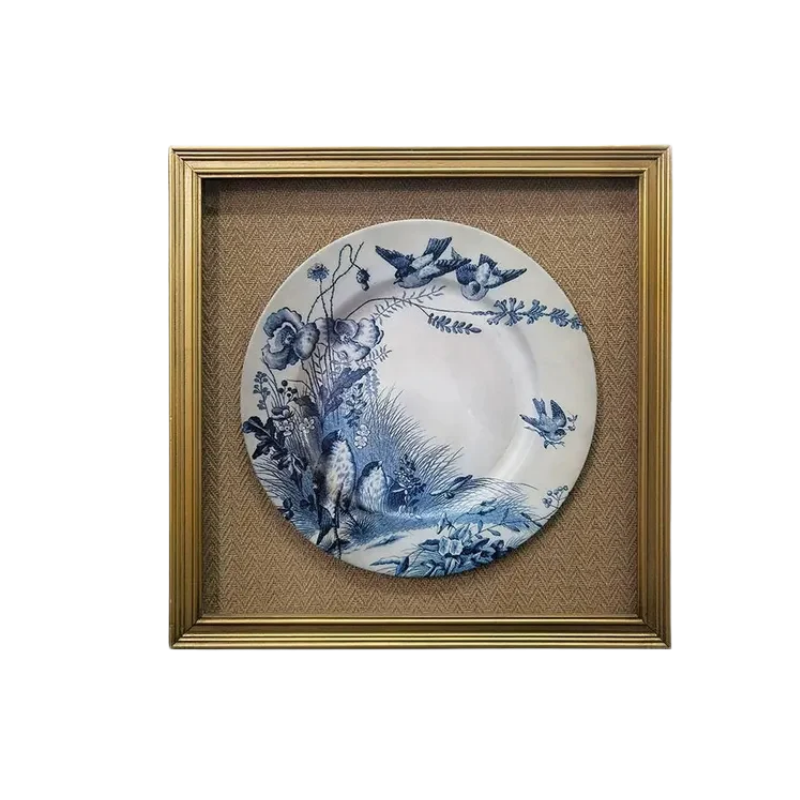 Framed print of a blue and white ceramic plate with bird and floral motifs in a gold frame.
