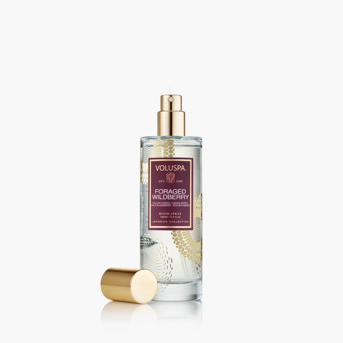 Voluspa Foraged Wildberry Room Spray in a clear glass bottle with gold floral patterns and cap.