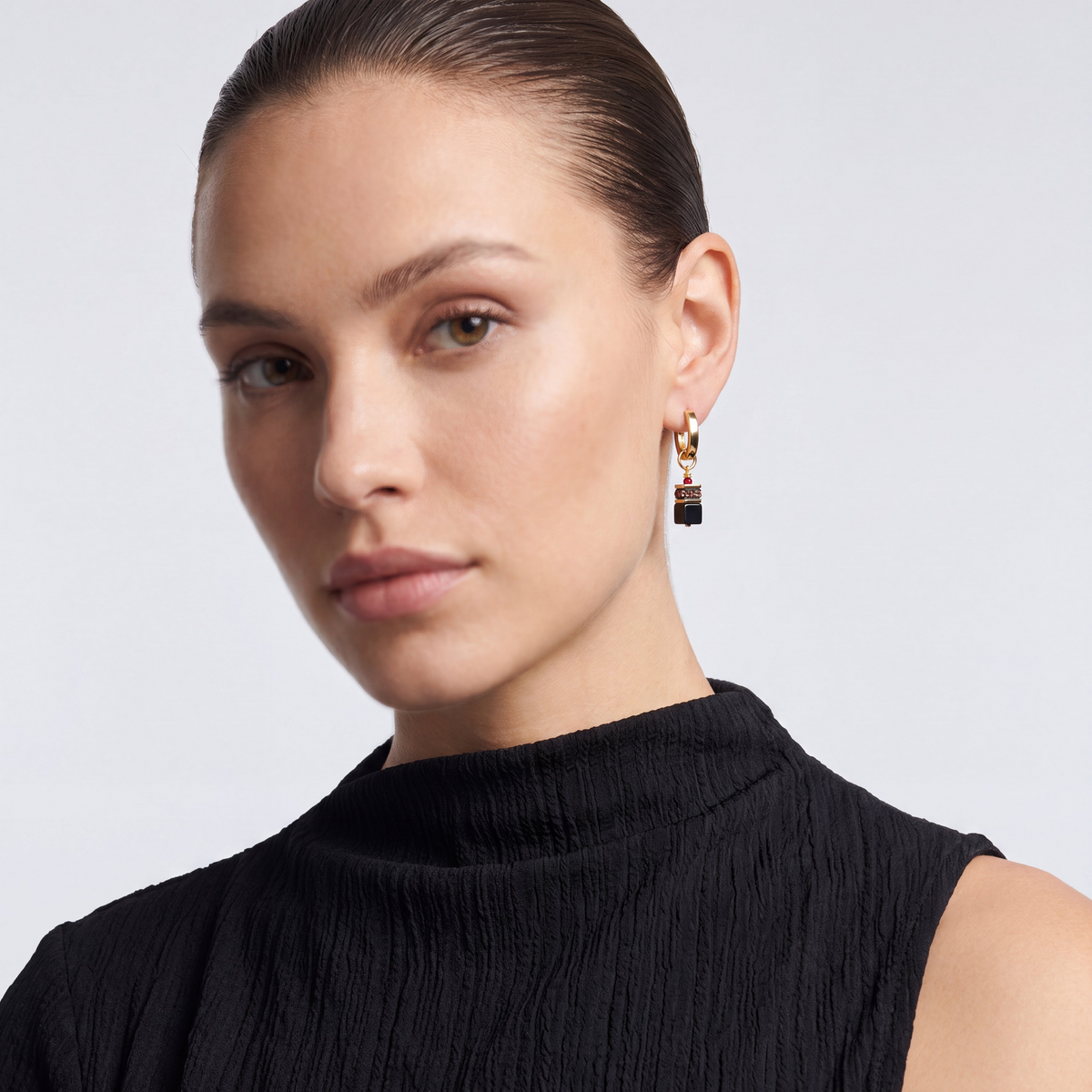Model wearing GeoCUBE Precious Classic Hoop Earrings with black onyx and ruby red accents.