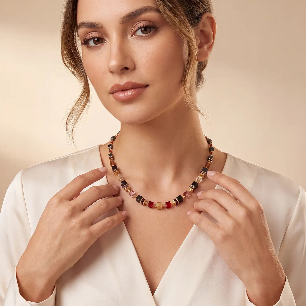 Woman wearing a GeoCUBE Precious Classic Necklace with black, ruby red, and gold cube elements.