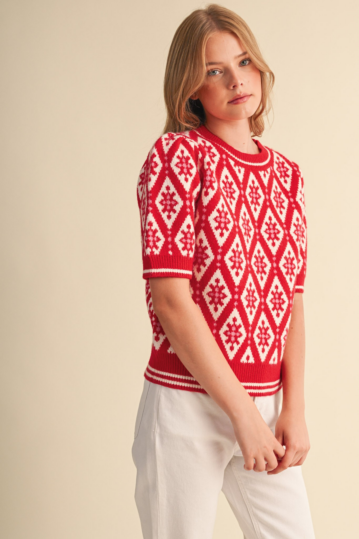 Woman wearing the Isabella red and white geometric knit short sleeve sweater with white pants.