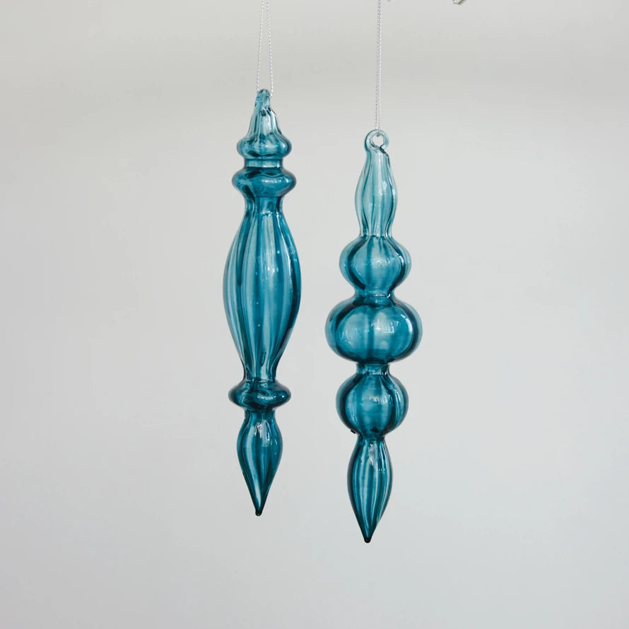 Two teal blue handcrafted glass finial ornaments with elegant ribbed and bulbous contours.