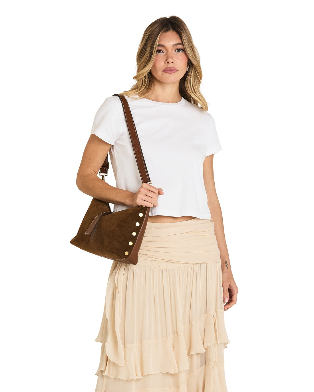 Woman wearing the Grace Med Bag in brown suede with gold rivets and a leather crossbody strap.