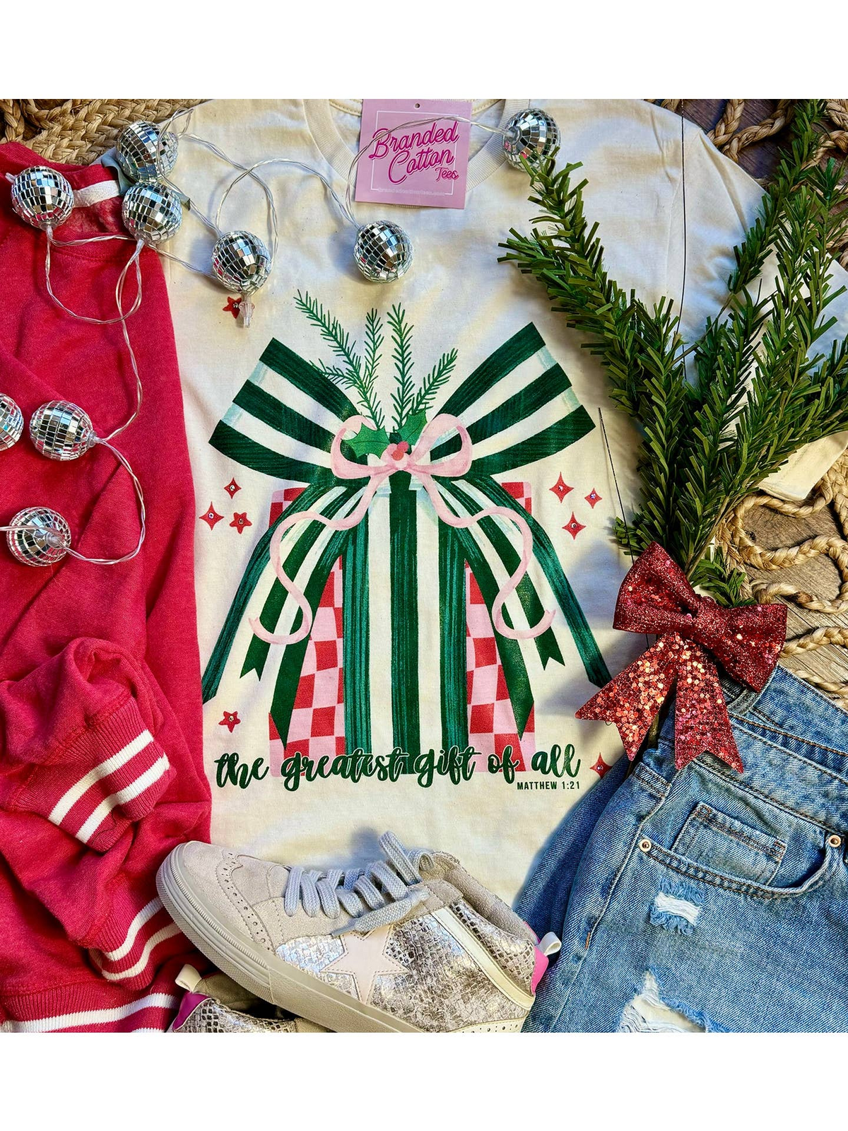 Greatest Gift T-Shirt with a green striped bow and gift box graphic, styled with jeans and sneakers.