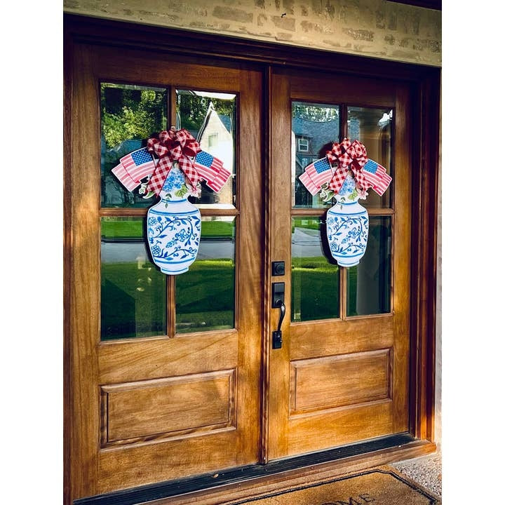 Two Betsy Ross patriotic flag vase door hangers on double wooden front doors.