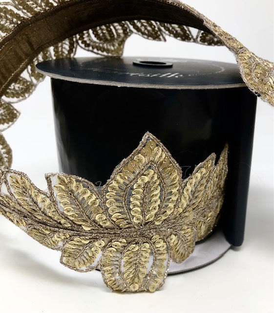 4 inch wide gold masquerade vine ribbon with sequined leaf patterns on a black spool.
