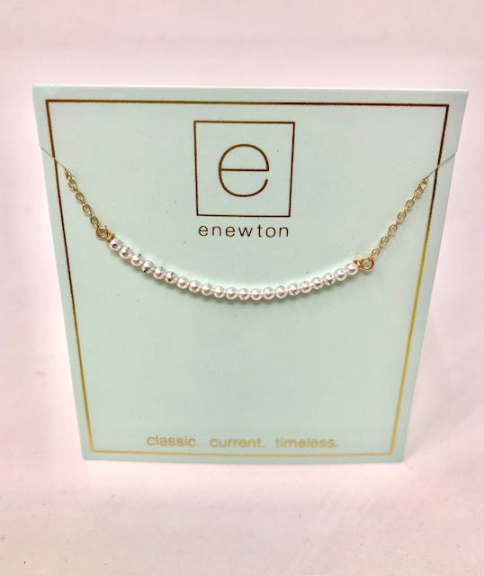 16-inch gold chain necklace with a curved row of small white pearls on an enewton display card.