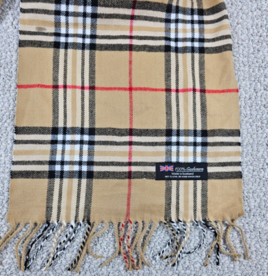Tan plaid cashmere scarf with a classic check pattern and fringe edges.