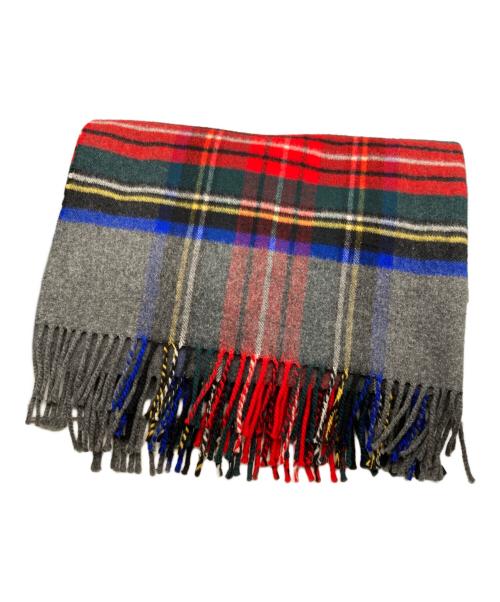 Folded plaid knitting pattern scarf with red, green, blue, and grey sections and fringed edges.