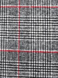 Close-up of a grey, black, and white plaid knitting pattern with thin red accent lines.