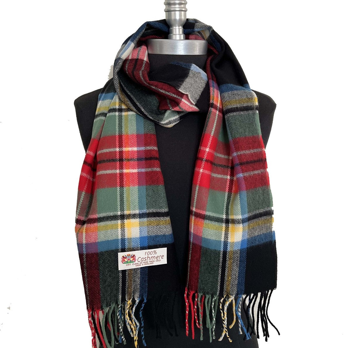 Plaid knitting pattern scarf in red, green, and black with fringe and a 100% cashmere label.