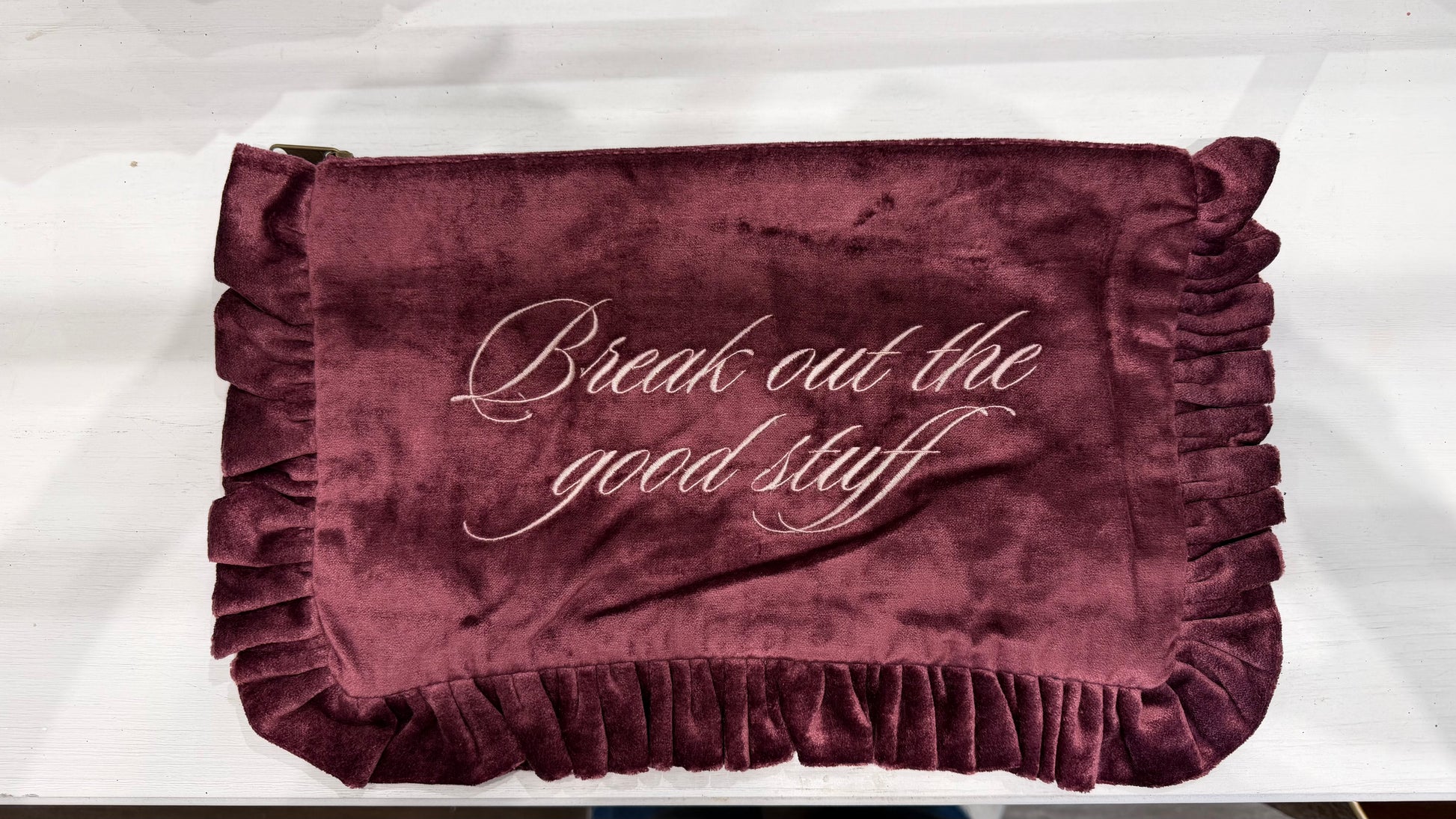 Burgundy velvet ruffle travel pouch with "Break out the good stuff" embroidered in white script.