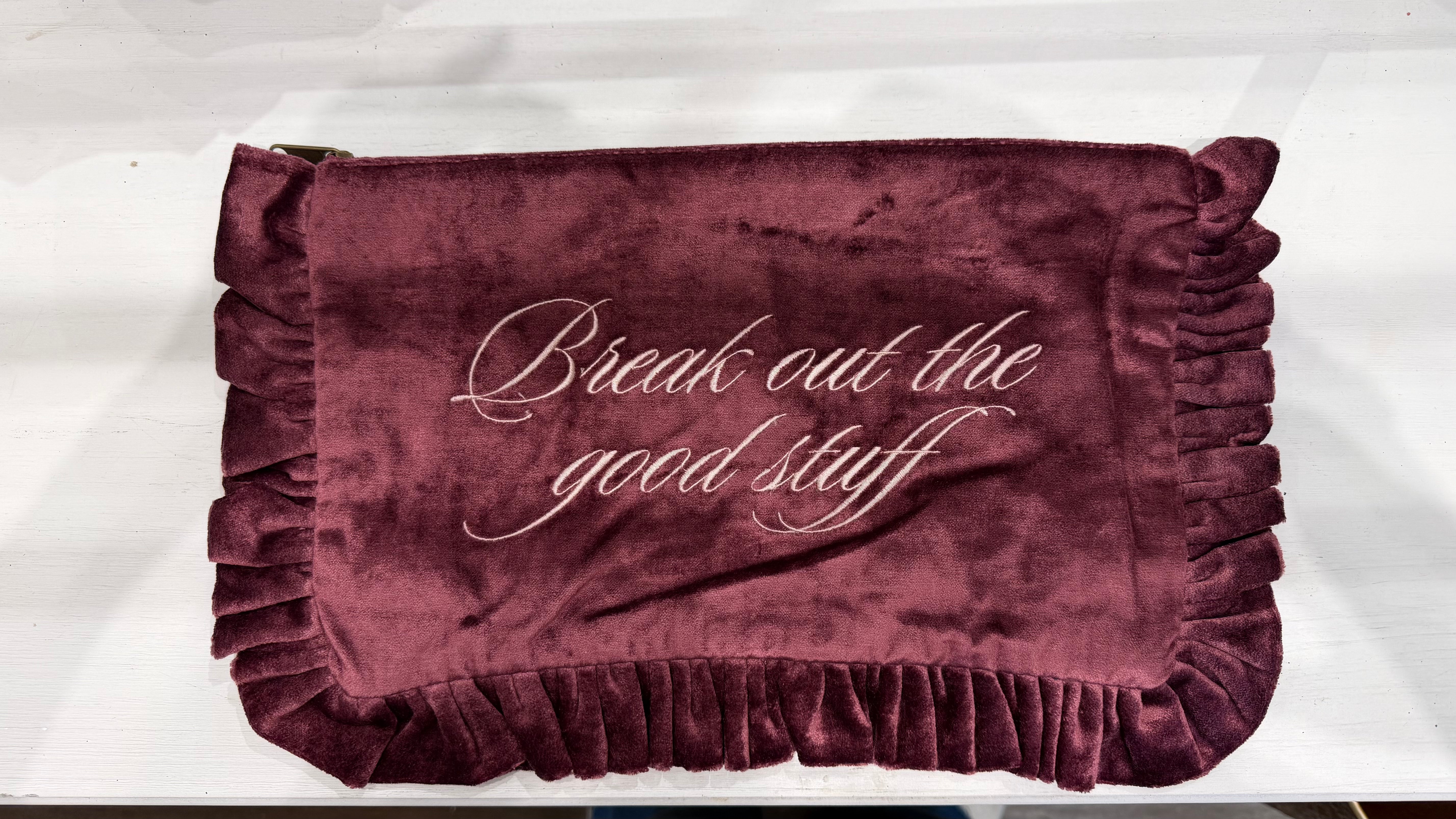 Burgundy velvet ruffle travel pouch with "Break out the good stuff" embroidered in white script.