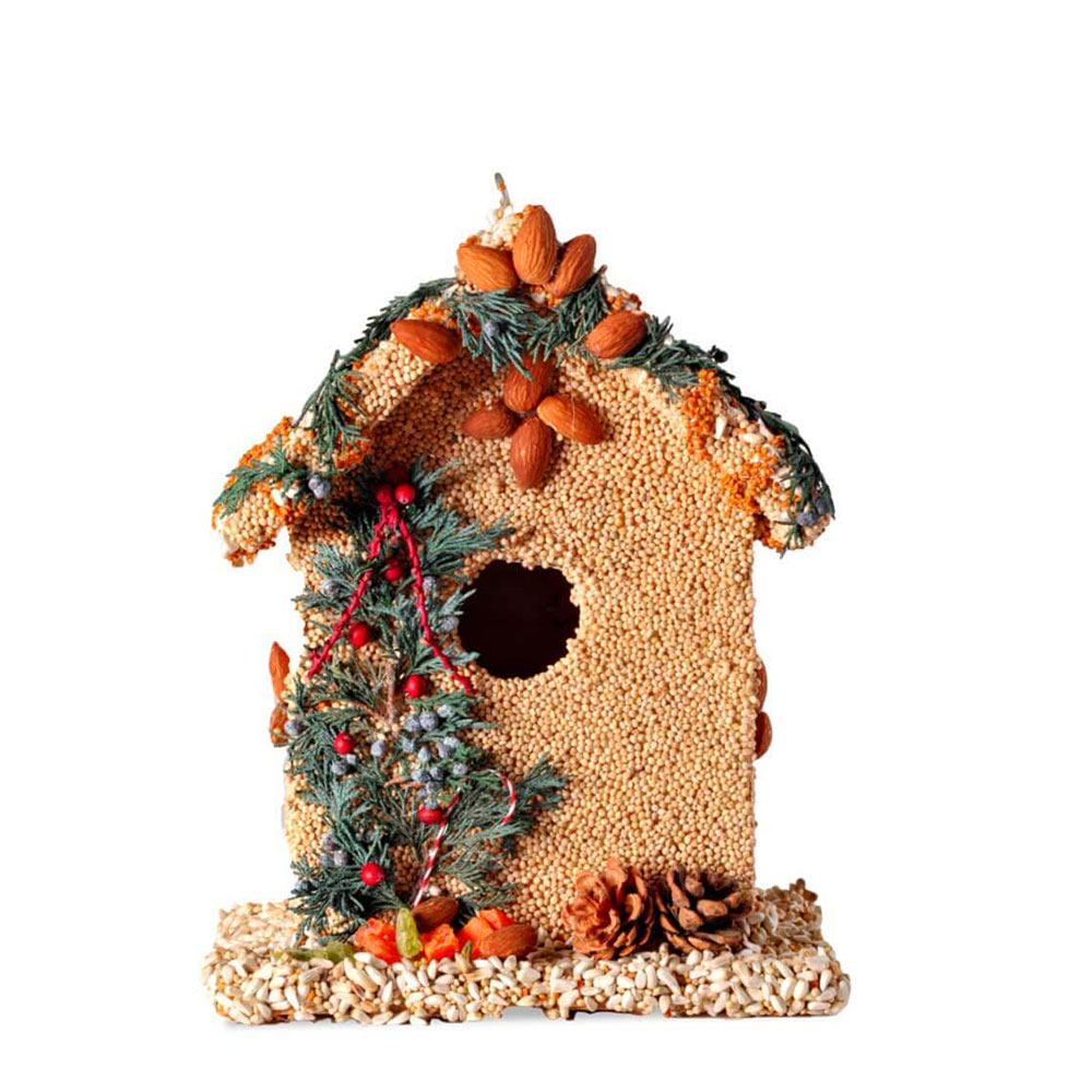 Juniper B&B birdhouse covered in birdseed, almonds, and juniper sprigs with pinecones at the base.