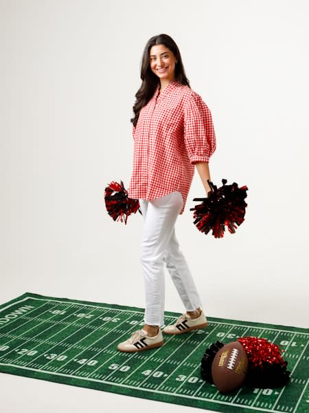 Woman in a red and white gingham Laura Top with ruffled collar and pleated sleeves.