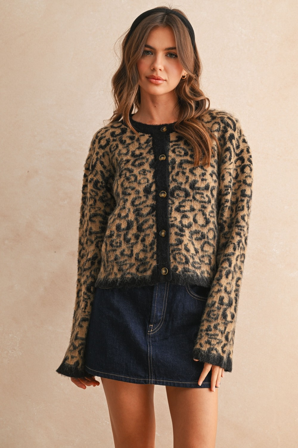 Woman wearing the Olivia Leopard Print Sweater Cardigan with a denim skirt and black headband.
