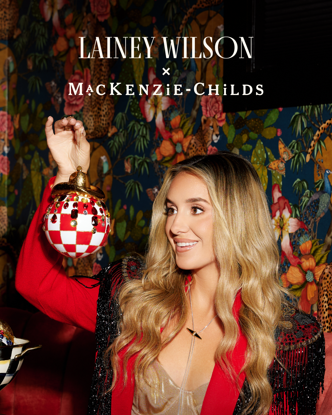 Lainey Wilson holding a red and white check glass cowboy hat ornament with jeweled accents.