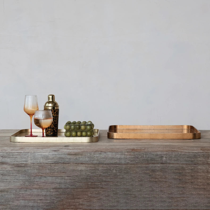 Set of two rectangular MDF lacquered trays with gold and copper foil finishes on a wooden surface.