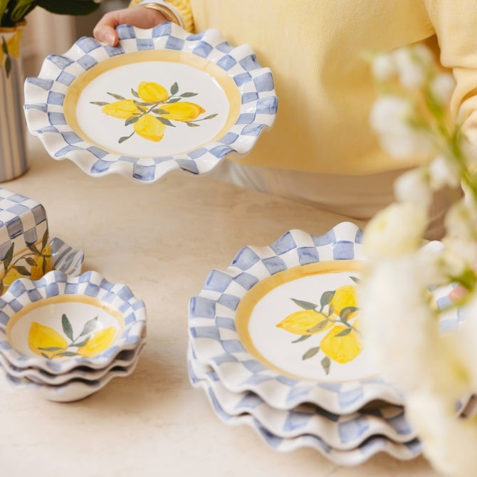 Ceramic cheese platter with a scalloped edge in cream color featuring subtle floral patterns.