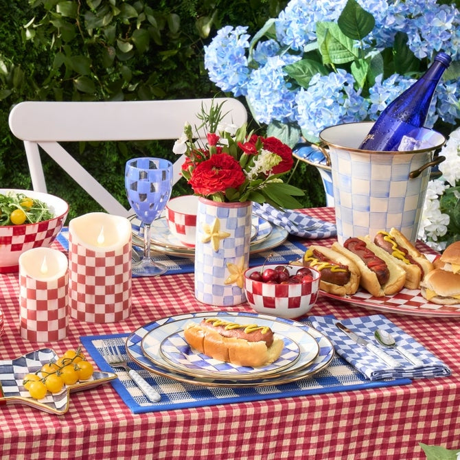 Hand-painted Mackenzie-Childs Star Vase with blue checks and yellow stars on a festive table.