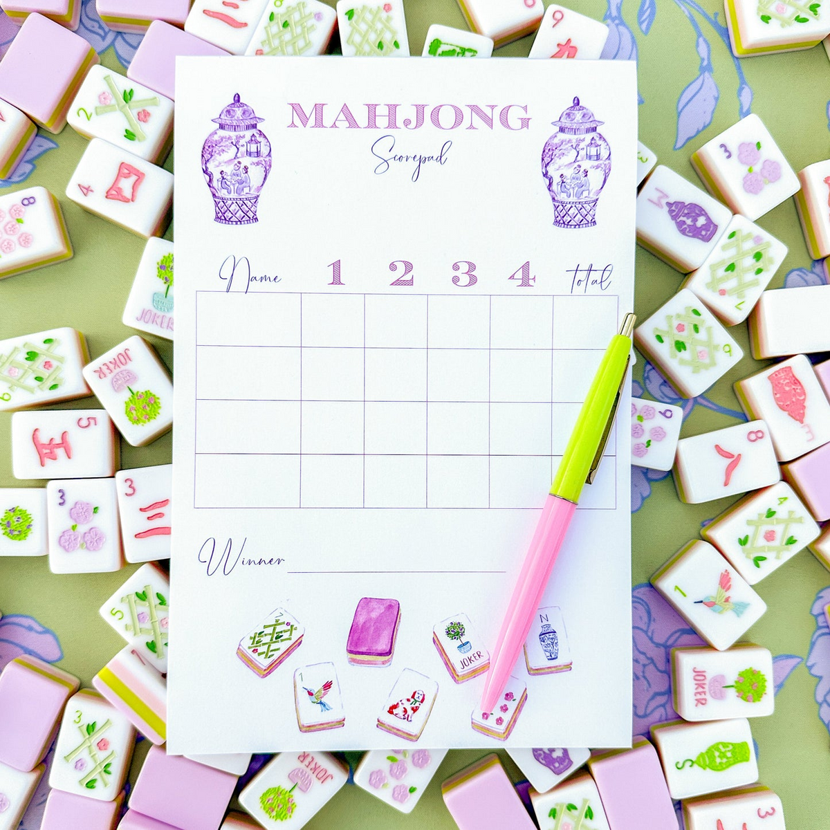 Mahjong Scorecard Pad with Taylor Tiles illustrations, a pink and yellow pen, and mahjong tiles.
