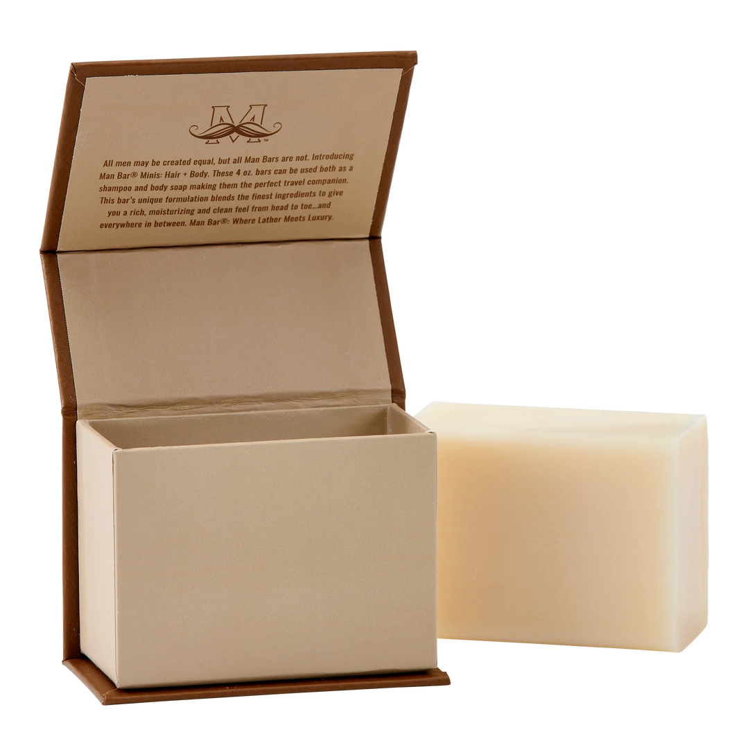 Man Bar Mini 4oz Cedar & Sandalwood soap bar next to its open brown and tan flip-top box.