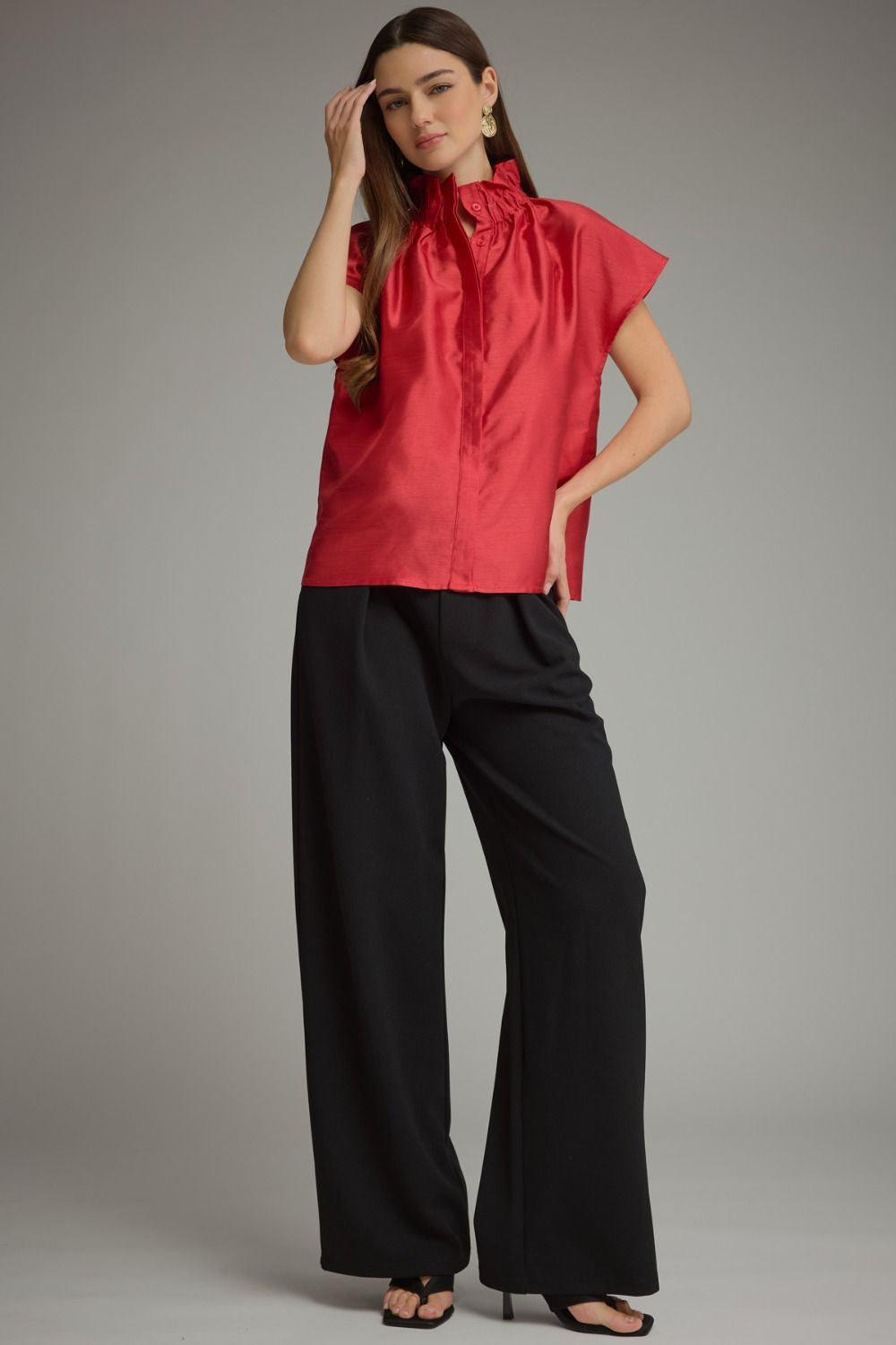 Woman wearing a red Maya solid cap sleeve top with a ruffled high neckline and black wide-leg pants.