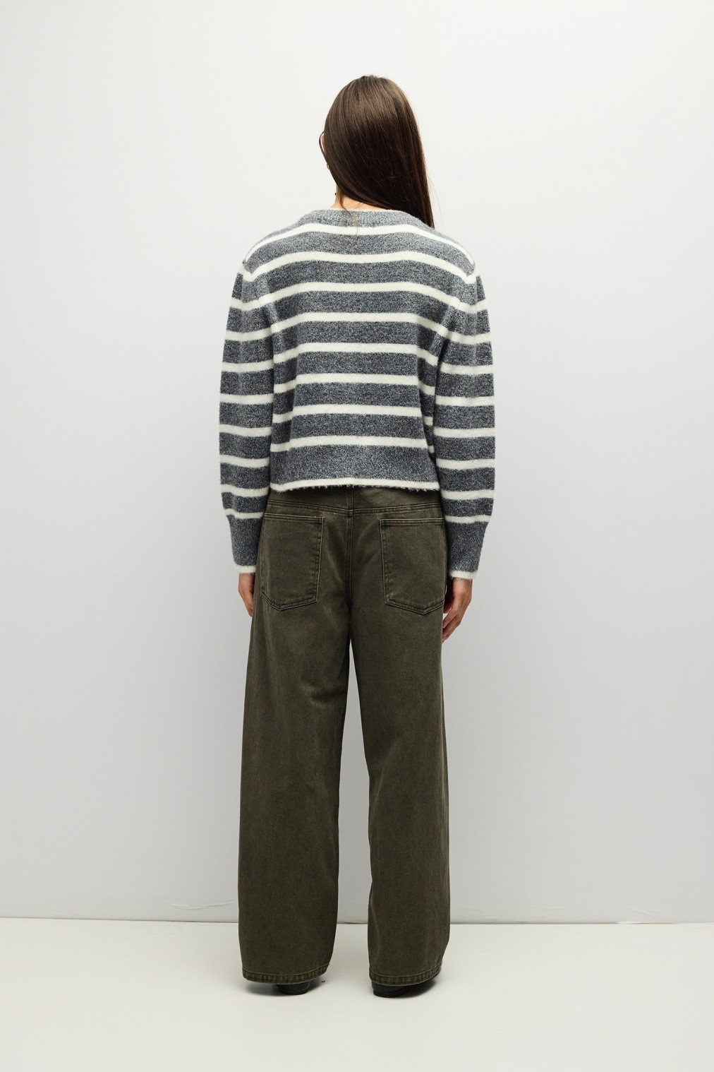 Back view of a person wearing the Natalia Sweater, a grey and white striped cropped boucle knit.