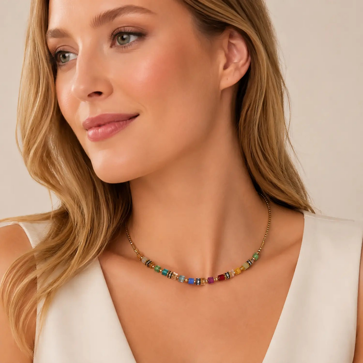 Woman wearing a gold necklace with small, colorful cube-shaped Swarovski crystals and beads.