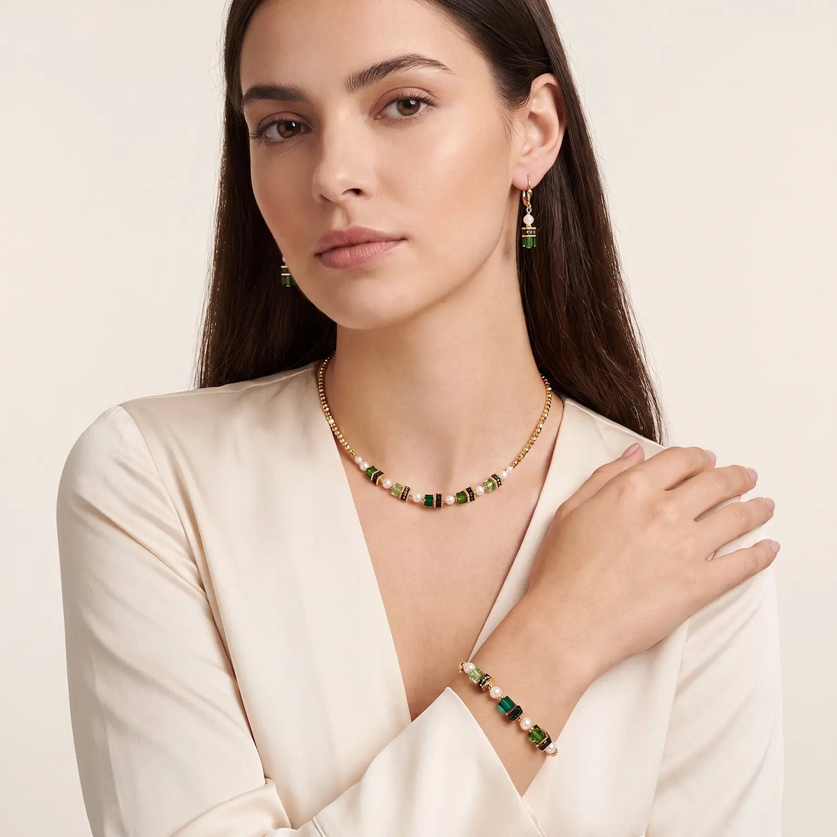 Woman wearing the Sparkling Princess gold-emerald necklace with matching bracelet and earrings.