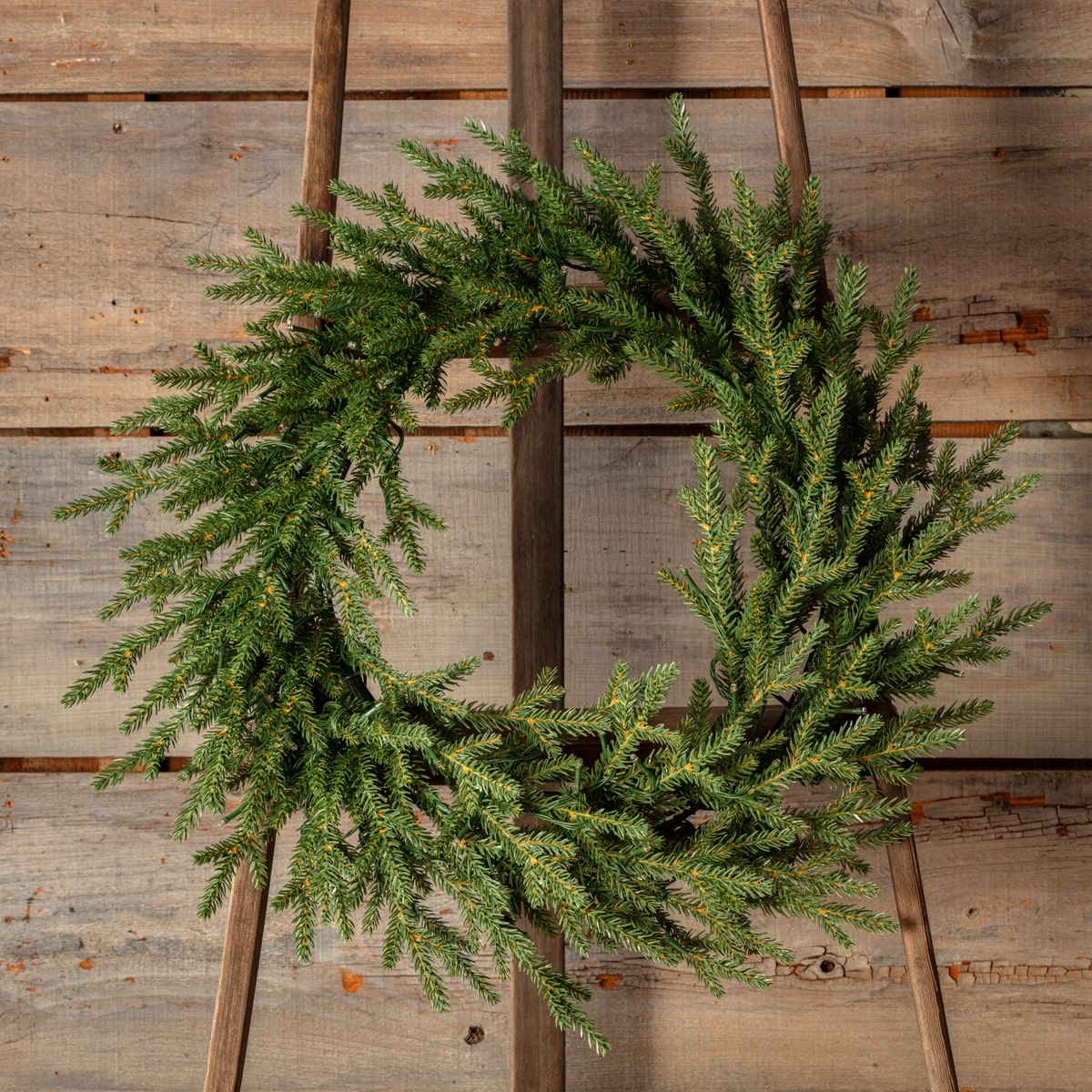 Olympia Fir 24-inch pre-lit artificial evergreen wreath displayed on a wooden easel.