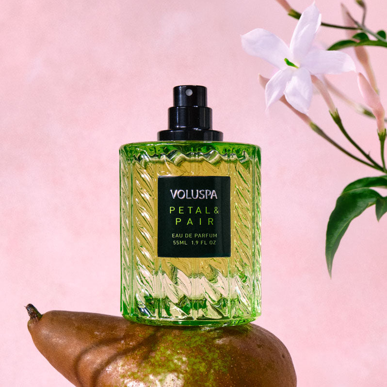 Voluspa Petal & Pair 55ml Eau De Parfum in a green textured glass bottle resting on a pear.