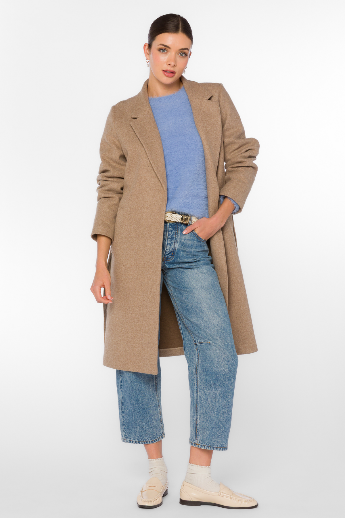 Woman wearing the Phaedra Coat in camel over a blue knit sweater and denim jeans.