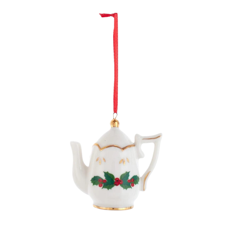 White porcelain teapot ornament with gold trim and holly berry design hanging from a red ribbon.