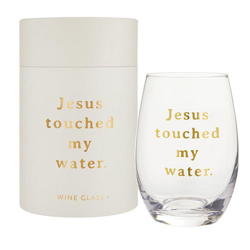 Stemless wine glass and gift tube with gold text reading "Jesus touched my water."