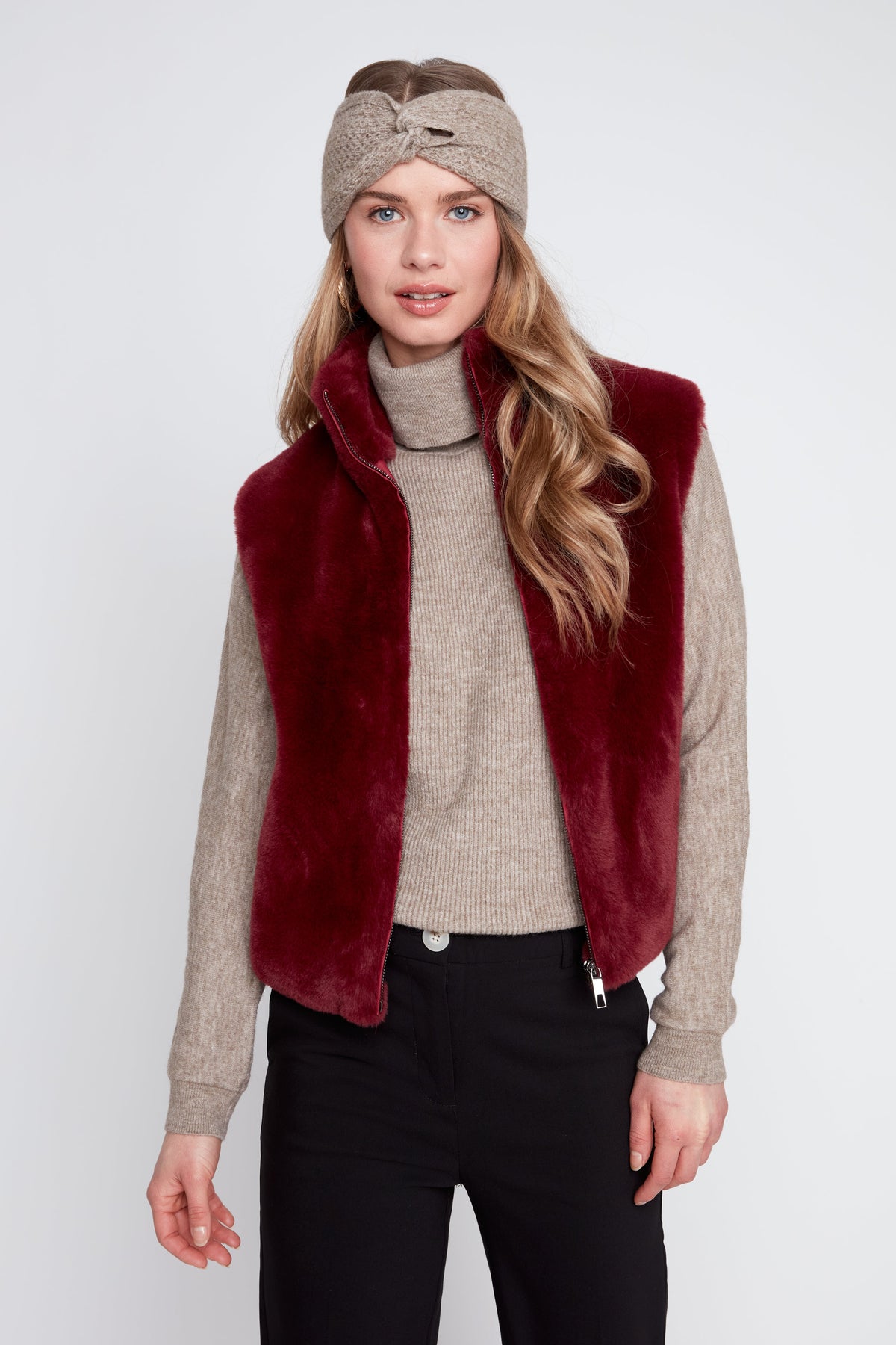 Woman wearing the Ella Solid Faux Fur Short Vest in cabernet over a beige turtleneck sweater.