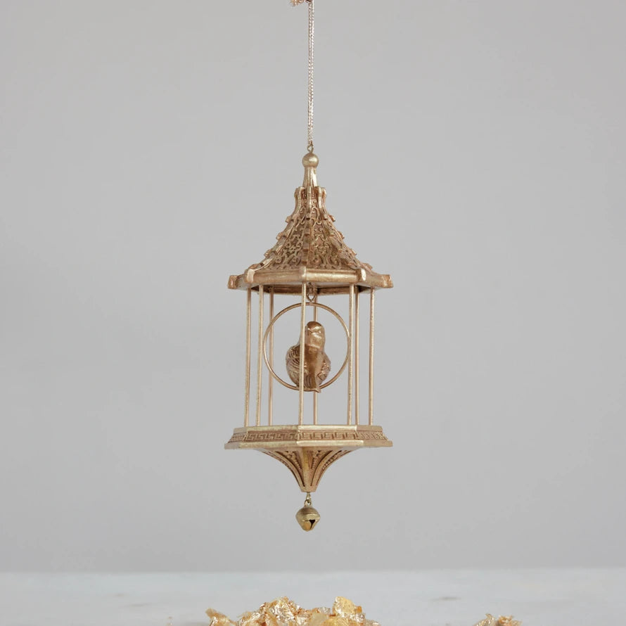 Gold resin birdcage ornament with a pagoda roof, sculpted bird inside, and a hanging bead detail.