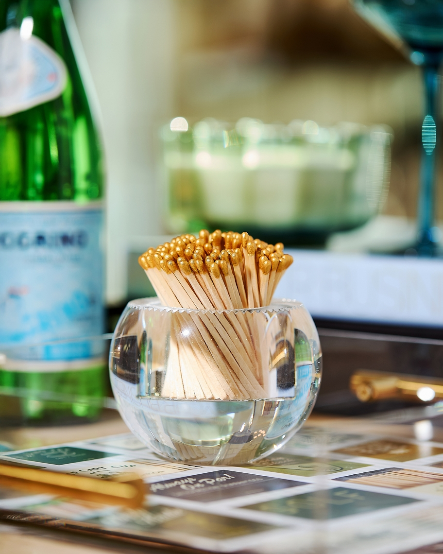 Round acrylic match striker with gold-tipped matches on a decorative tray.