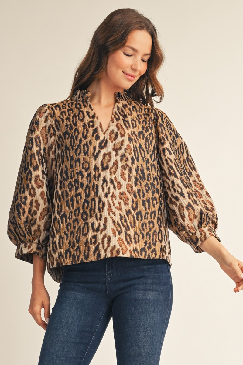 Woman wearing the Eliana Ruffled Neck Leopard Jacquard Top with dark blue jeans.