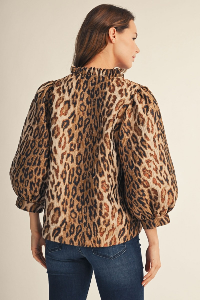 Back view of a woman wearing the Eliana leopard jacquard top with ruffled neck and puff sleeves.