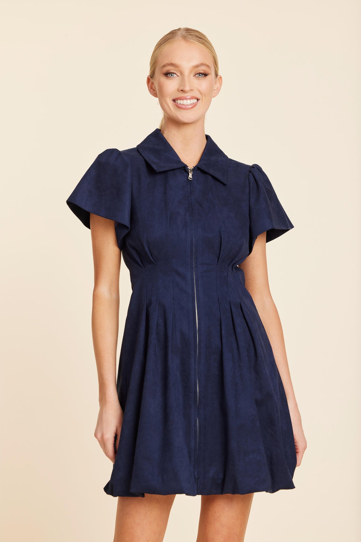 Woman wearing the Olivia navy blue faux suede bubble dress with a front zipper and short sleeves.