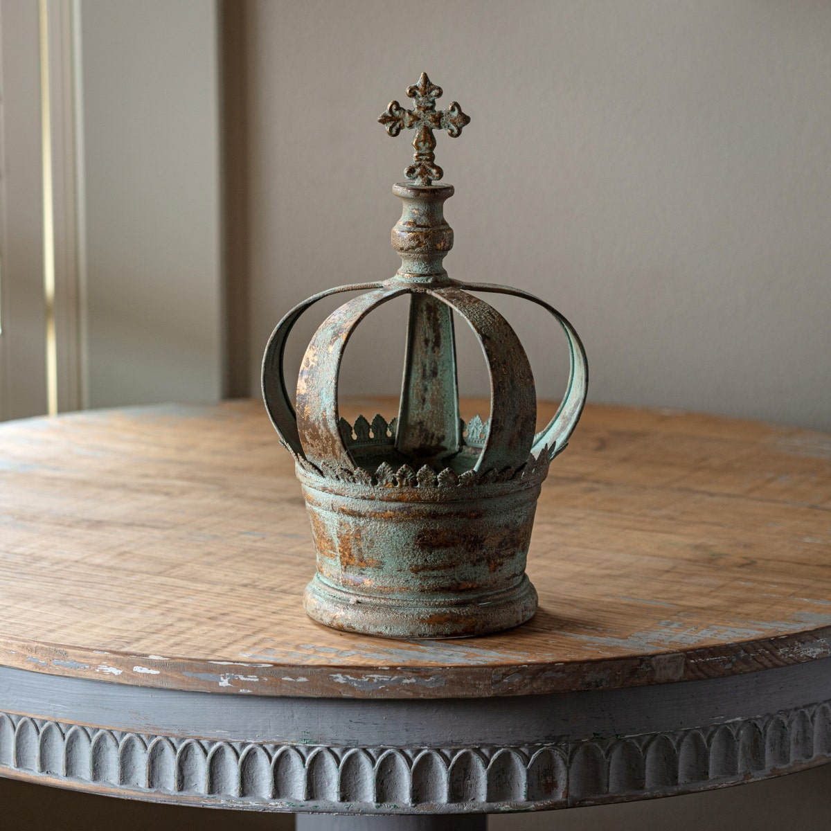 Saint's Crown with an aged green and gold patina finish, topped with a cross on a wooden table.