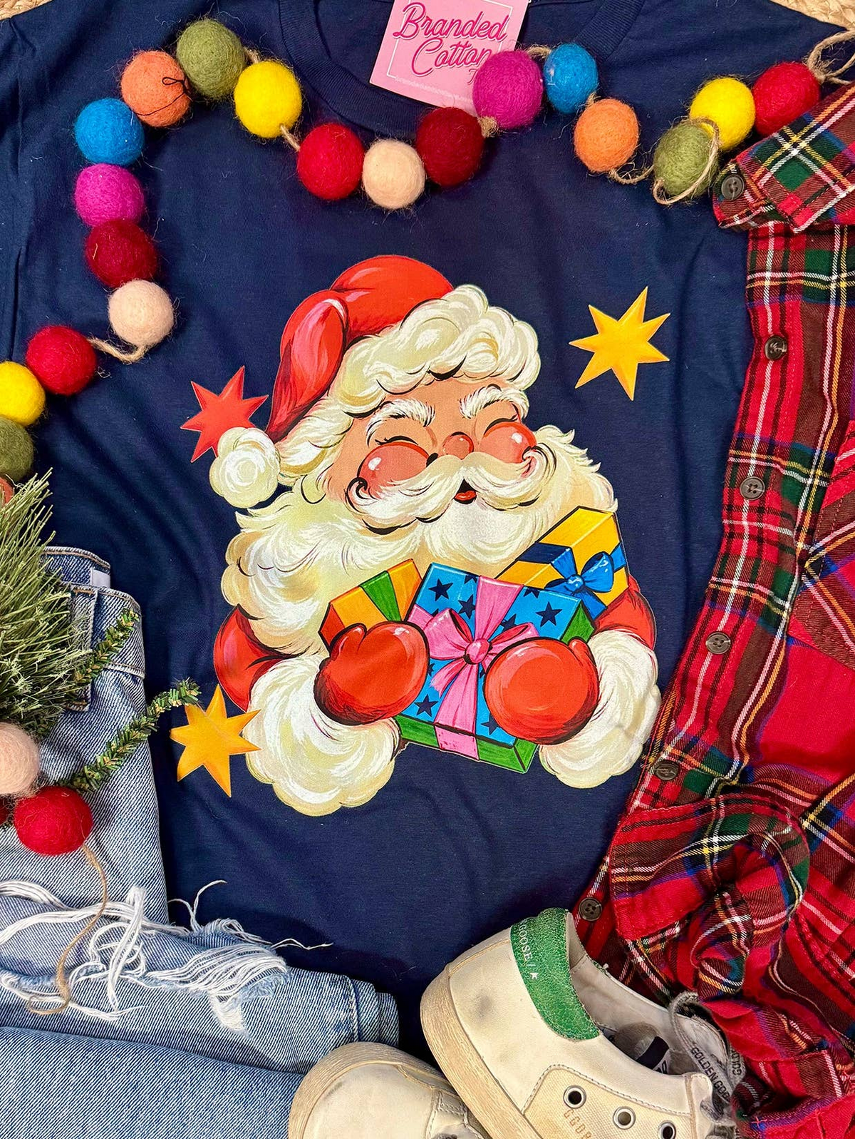 Navy blue t-shirt featuring a vintage-style Santa Claus holding colorful presents and yellow stars.
