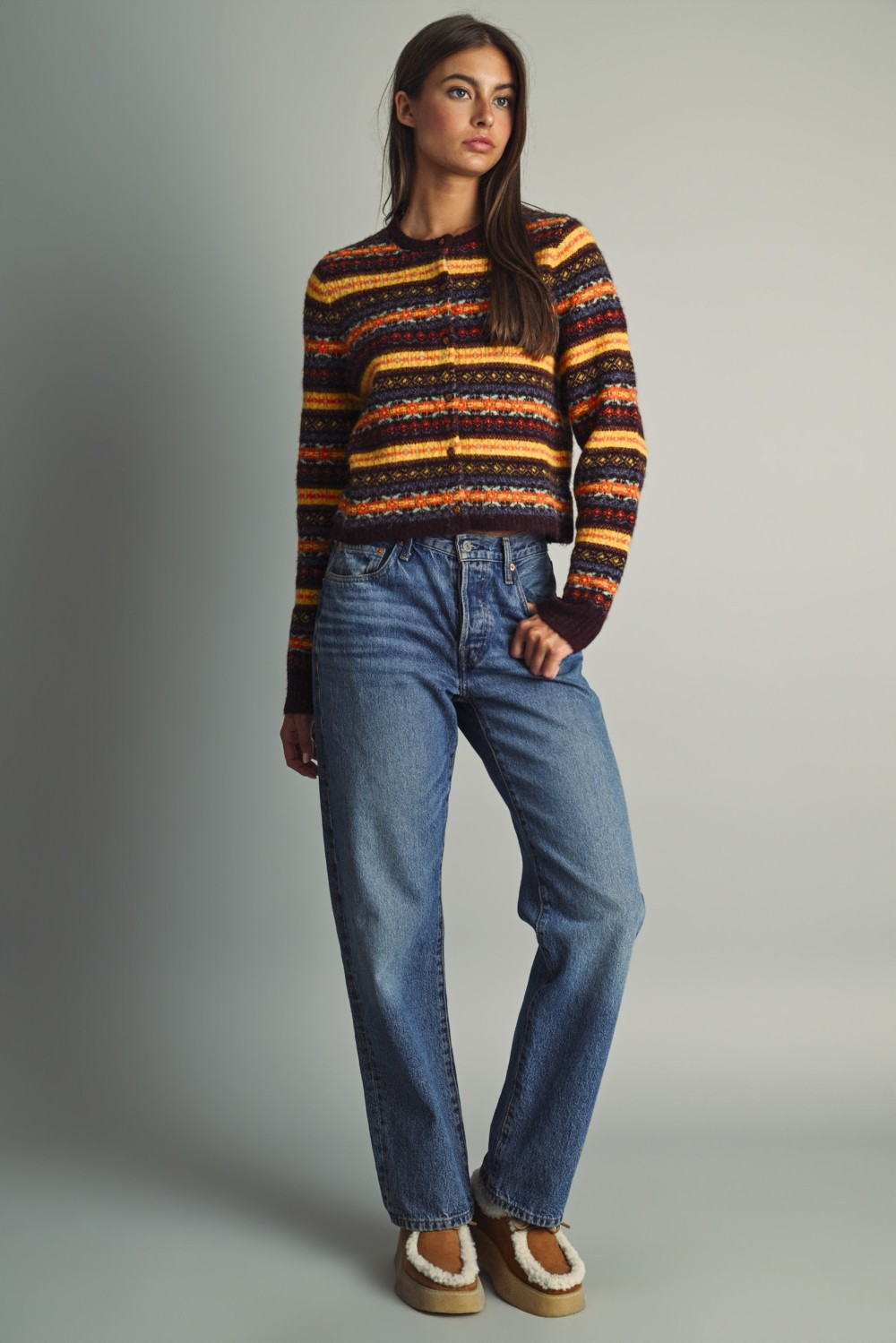 Woman wearing the Althea multicolored Fair Isle cropped knit cardigan with high-waisted blue jeans.