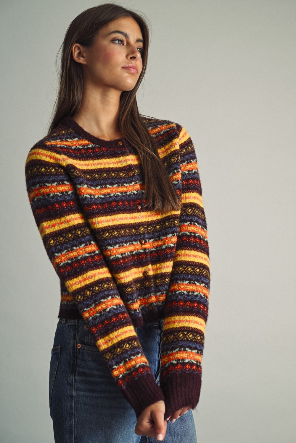 Woman wearing Althea multicolored Fair Isle pattern cropped knit cardigan with blue jeans.