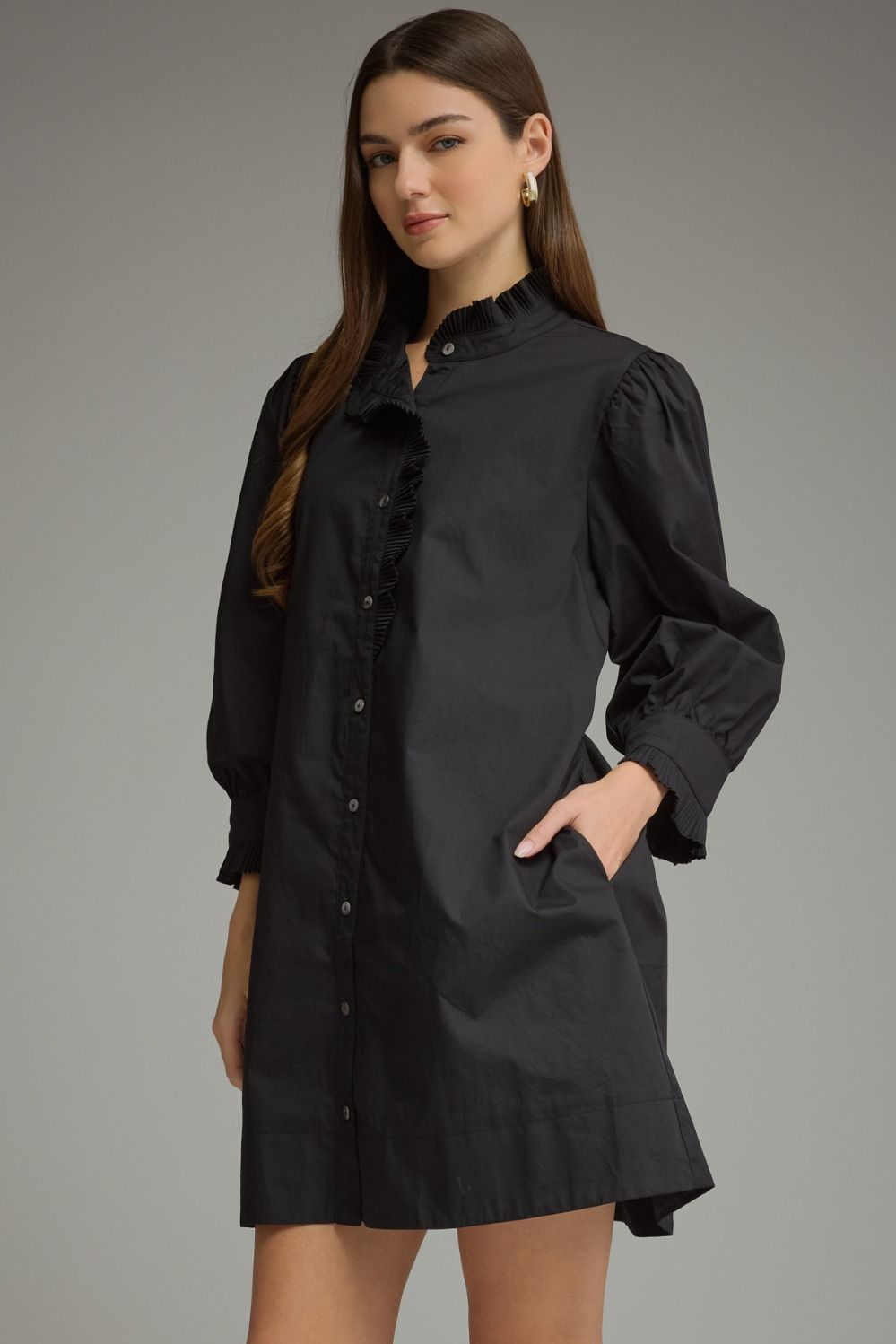 Woman wearing the Agnes black mini dress with ruffled high neckline and 3/4 puff sleeves.