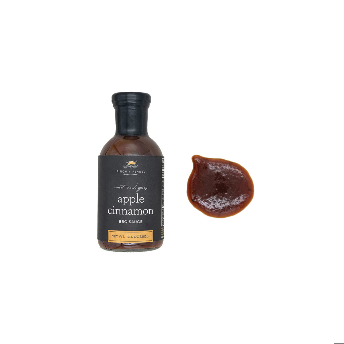 A bottle of Finch + Fennel Sweet and Spicy Apple Cinnamon BBQ Sauce next to a dollop of the sauce.